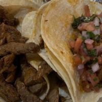 Tacos De Carne Asada
 · Three soft corn tortillas tacos filled with tender strips of grilled steak. Served with frie...