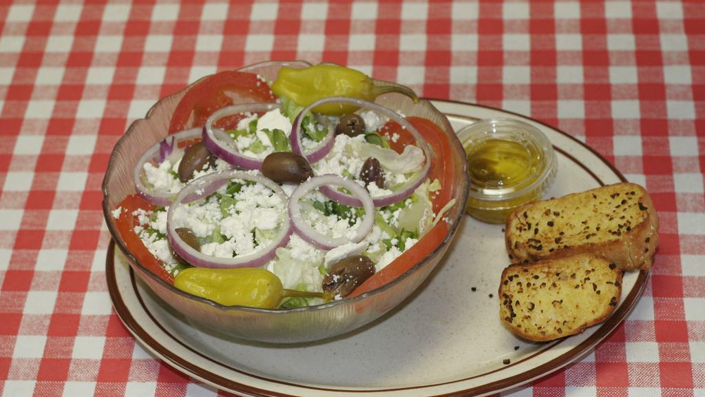 Greek Salad · Fresh garden green, tomato, onion, Greek Kalamata olives, green peppers topped off with feta cheese pepperoncinis and a sprinkle of Greek herbs (oregano, basil and others), Served with Greek homemade dressing and crackers.