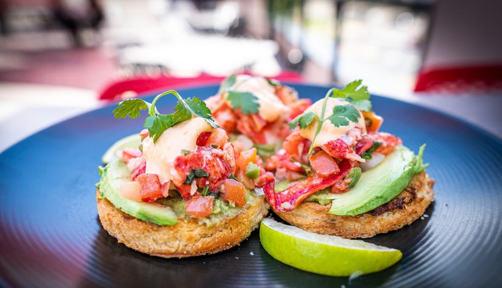 Lobster Avocado Toast · Parmesan crusted brioche toast spread with house-made guacamole then topped with lobster meat tossed with pico de gallo, finished with slice of fresh avocado and lime.