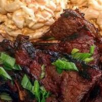 Kal-Bi  · Grilled Thin Cut Beef Short Ribs in Korean Marinade. Served with Rice and Choice of Mac Sala...