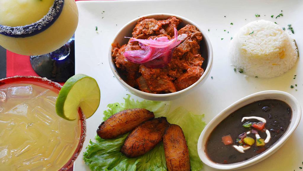 Cochinita Pibil · Cochinita pibil this traditional Mexican, slow-roasted pork dish from the Yucatan peninsula is of Mayan origin. Preparation involves marinating the meat in a strongly acidic citrus juice and Mexican spices. Served with white rice, black beans and sweet plantains. Tortillas of your choice.