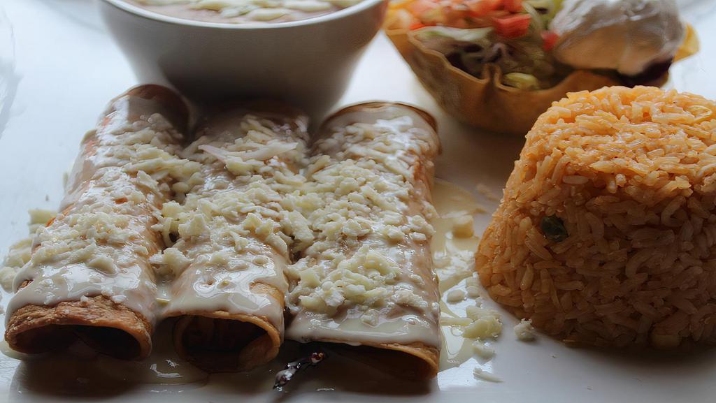 Flautas De Pollo · Four rolled corn tortillas deep fried and stuffed with chicken, topped with nacho cheese. Served with rice, beans, lettuce, tomatoes, sour cream, and fresh white cheese.