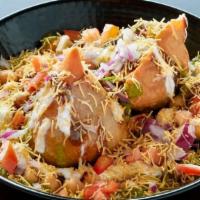 Samosa Chaat · Hot, flaky samosa blanketed with chickpeas and red onion, swirled with mint cilantro and tam...