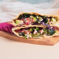 Hummus Pita Sandwich · Hummus with shredded cabbage, diced tomato and cucumber, and a tahini drizzle wrapped in a f...