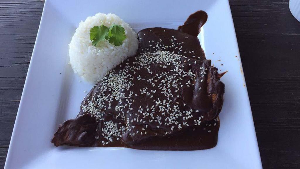 Guajolote En Mole · Roasted turkey breast smothered in mole sauce and white rice.