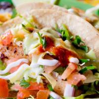 Fish Soft Tacos · Corn tortillas garnished with cabbage, tomato, onions, cilantro, spicy red sauce, and white ...