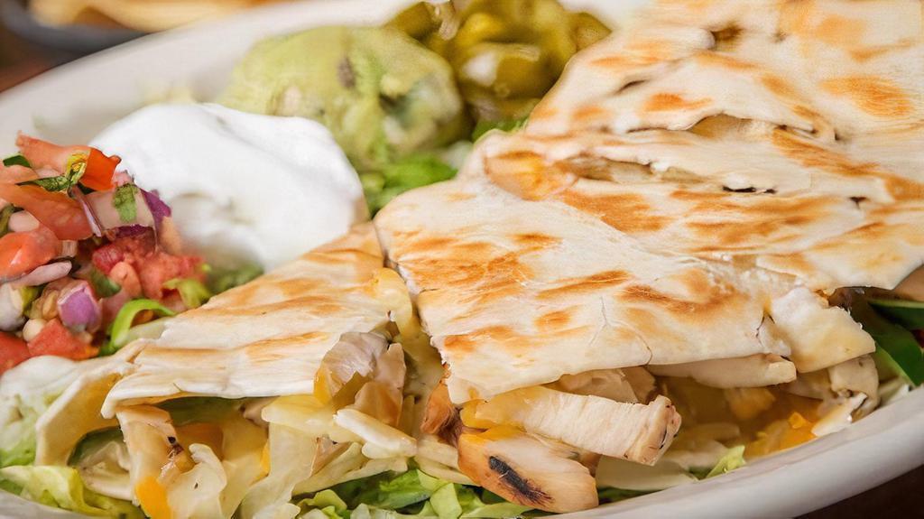 Quesadillas · Grilled flour tortillas stuffed with shredded monterey jack, Cheddar cheeses, poblano peppers, caramelized onions, and fajita chicken or fajita beef. Served with pico de gallo, jalapeños, guacamole and sour cream.