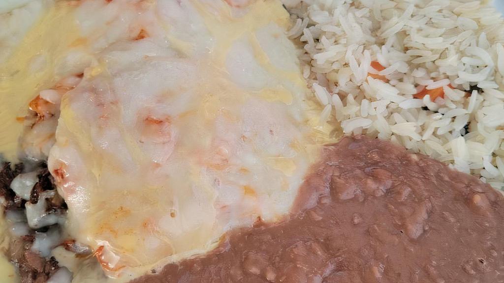 Brisket Enchiladas · Two cherry wood smoked brisket enchiladas, topped with our chipotle sauce and drizzled with queso. Served with jasmine rice pilaf and refried beans.