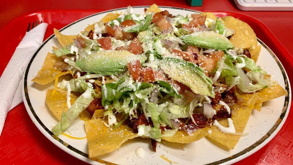 Nachos · Our delicious homemade nacho chips, topped with refried beans the meat of your choice, and salad.