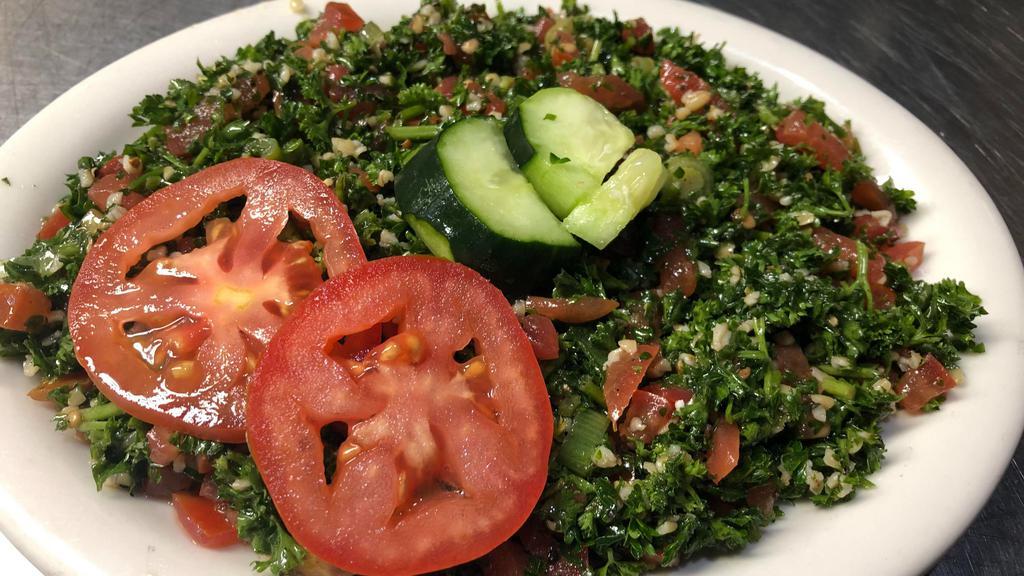 Tabouli Salad · A traditional Lebanese mediterranean salad made with fresh parsley, green onions tomatoes, and bulgur, served with a lemon olive oil dressing.