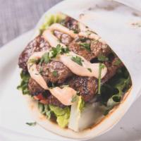 Kafta Kebab Gyro · Grilled ground lamb and beef rissole topped with tahini sauce and wrapped in a soft, warm pi...
