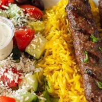 Kafta Kebab Plate · Two kafta kebab skewers served with a bed of basmati rice and Greek salad.
