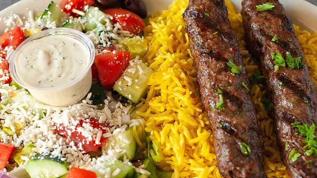 Kafta Kebab Plate · Two kafta kebab skewers served with a bed of basmati rice and Greek salad.