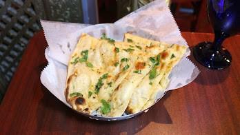 Garlic Naan · Freshly baked naan bread topped with chopped garlic and butter.