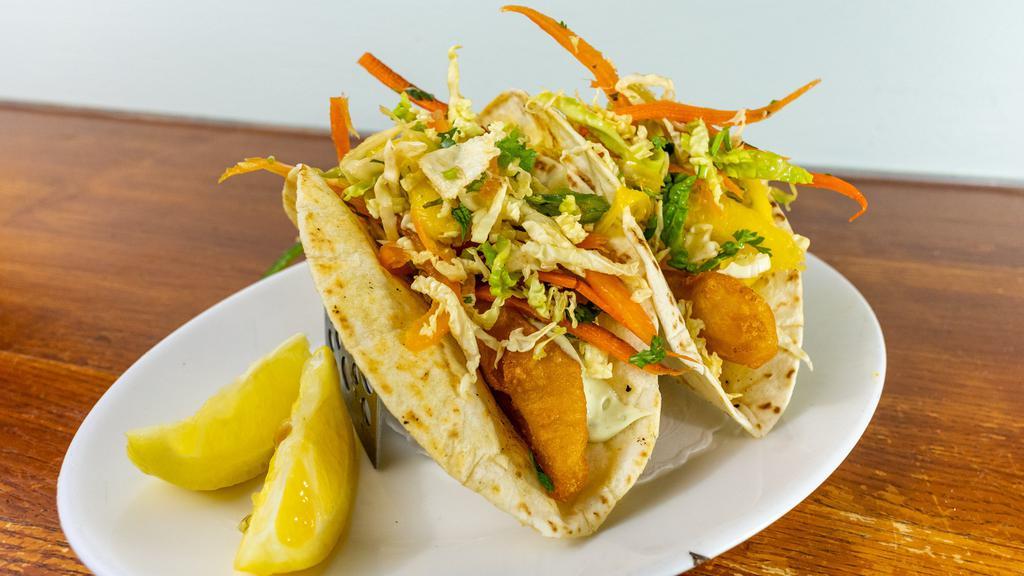 Baja Fish Tacos · Tempura battered mahi-mahi fillet wedges (2) layered with a house-made tropical cabbage slaw with cilantro, finished with a jalapeño avocado aioli served in soft flour tortillas.